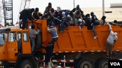 Pekerja migran asal Afrika berupaya naik ke truk setibanya di pelabuhan Misrata dalam operasi evakuasi yang diorganisir IOM.