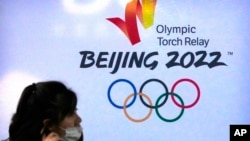 一名戴著口罩的女子走過北京2022冬季奧運會標誌。 (2021年12月9日美聯社資料照)