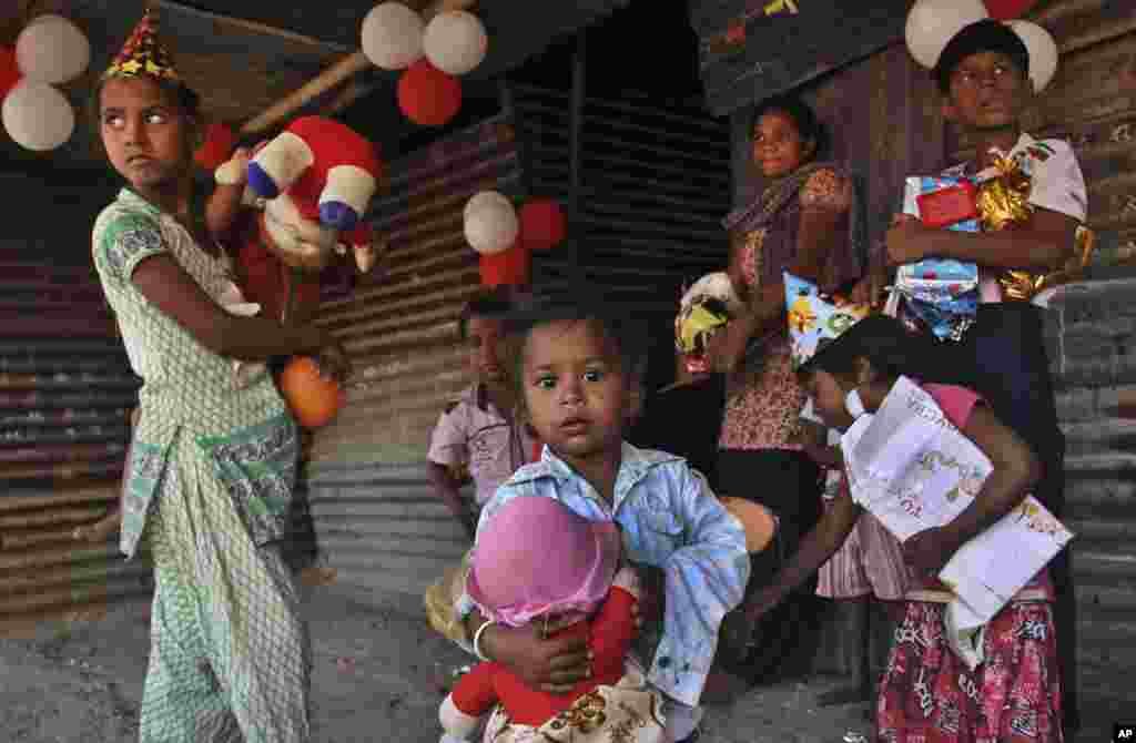 Anak-anak di wilayah kumuh India memegang mainan dan hadiah yang mereka terima dari sebuah LSM dalam perayaan Natal di Ahmadabad (25/12).