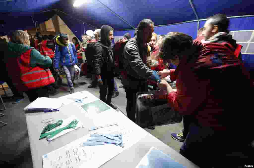 Colored bracelets are placed on the wrist of migrants at a processing center on the second day of their evacuation and transfer to reception centers in France, during the dismantlement of the camp called "the jungle" in Calais, France, Oct. 25, 2016.