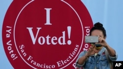 A woman takes a photo in front of an I Voted sign at a San Francisco Department of Elections voting center in San Francisco, Nov. 2, 2020.