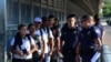FILE - U.S. Customs and Border Patrol officials wait to hand asylum seekers over to Mexican officials as they are returned under the so-called Remain in Mexico program, on the international bridge between Laredo, Texas, and Nuevo Laredo, Mexico, July 10, 
