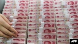 A teller counts yuan banknotes in a bank in Lianyungang, east China's Jiangsu province on August 11, 2015.