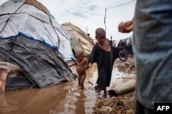 FILE - Two Fulani children walk across a puddle in an internally displaced people's (IDP) camp in Faladie, Mali, May 16, 2019.