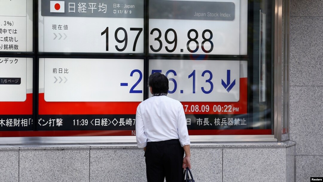 A man looks at an electronic board showing Japan's Nikkei average outside a brokerage at a business district in Tokyo, Aug. 9, 2017. 