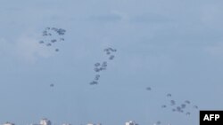 Sejumlah bantuan kemanusiaan untuk wilayah Gaza utara diterjunkan dari udara seperti yang terlihat dari perbatasan antara Israel dan Gaza pada 7 Maret 2024. (Foto: AFP/Jack Guez)