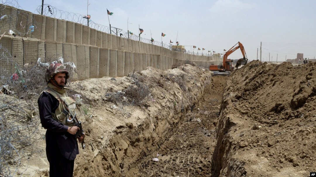 FILE - A Pakistani border guard stands guard as an excavator digs a trench along the Pakistan-Afghanistan border at Chaman post in Pakistan, May, 16, 2014.