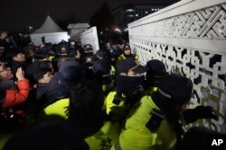 Para pedemo mencoba memasuki kompleks parlemen yang dihalangi oleh para polisi di Seoul, Korea Selatan, Selasa, 3 Desember 2024. (Foto: Lee Jin-man/AP Photo)