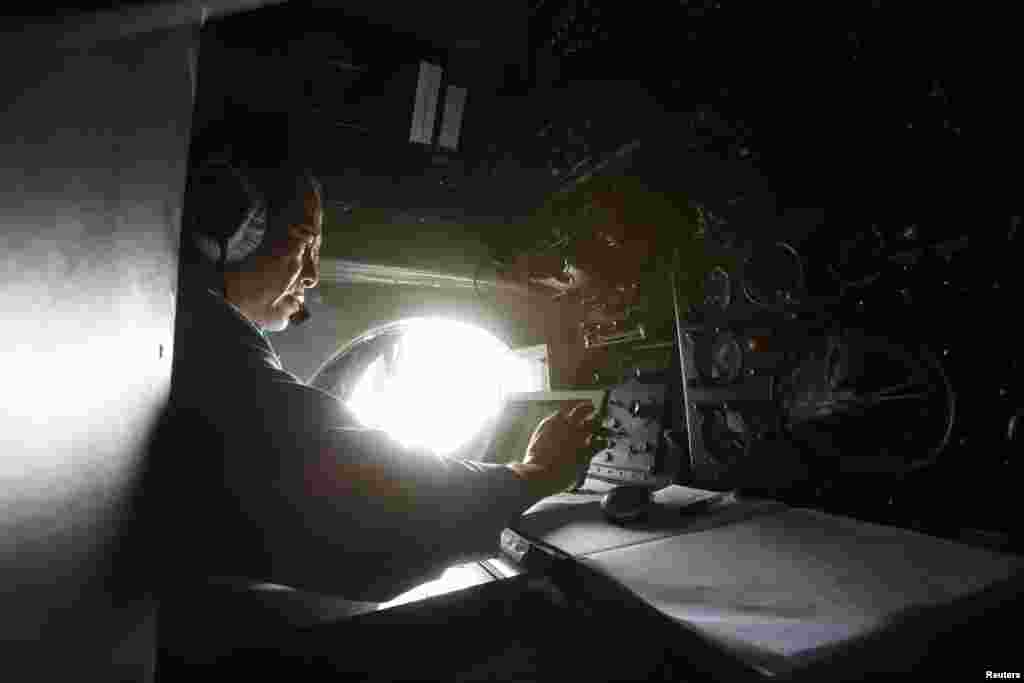 Military officer Duong Van Lanh works onboard a Vietnamese airforce AN-26 during a mission to find the missing Malaysia Airlines flight MH370 off Tho Chu islands March 11, 2014.