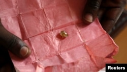 FILE - A man displays a rough diamond from the Boda region, for sale in Bangui, Central Africa Republic, May 1, 2014.
