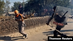 A policeman chases away a farmer during a protest against the newly passed farm bills at Singhu border near Delhi, India, Nov. 27, 2020.