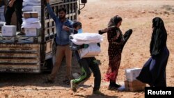 FILE - A worker holds bags and a box of humanitarian aid in the opposition-held Idlib, Syria June 9, 2021.