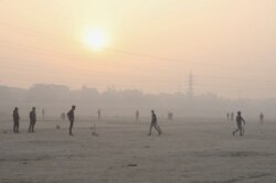 People play cricket on the floodplains of the Yamuna river on a smoggy morning in New Delhi, India, Nov. 17, 2021.