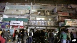 Warga berkumpul di depan sebuah mall di Baghdad, Senin (11/1). Kawanan bersenjata menembaki para pengunjung sebelum meledakkan diri di sebuah pusat perbelanjaan Baghdad, menewaskan sedikitnya 18 orang.