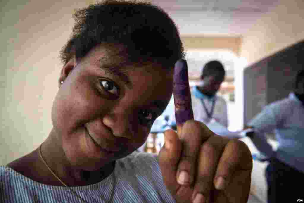 A woman shows off her inked finger after casting her ballot in Freetown, Sierra Leone, March 7, 2018. (Photo: Jason Patinkin / VOA)