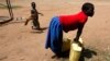 FILE- A girl prepares to lift a jerry can of water onto her head in the village of Loro in the Oyam district of northern Uganda. 