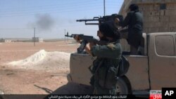 This undated image posted online July 18, 2016, by supporters of the Islamic State militant group on an anonymous photo-sharing website shows IS fighters firing weapons during clashes with the Kurdish-led Syria Democratic Forces in Manbij, in Aleppo province, Syria.