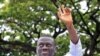 Uganda's Forum for Democratic Change leader Kizza Besigye waves to his supporters as he is blocked from driving to work in Kampala, prior to his arrest at gunpoint, April 28, 2011