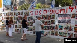 Warga Israel berdiri di depan tembok di Tel Avivdengan poster mendukung para sandera yang diculik kelompok Islam Palestina Hamas, di tengah konflik di Gaza antara Israel dan Hamas, 23 April 2024. 