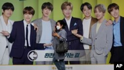 韩国首尔，一名戴着口罩的女子走过一块展示韩国K-Pop组合防弹少年团（BTS）的广告牌（2020年9月30日）。