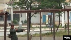 Seorang anggota pasukan keamanan Suriah menembakkan senjatanya ke arah demonstran anti pemerintah di kota Hama, Jumat (20/5).