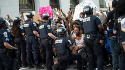 A man screams with emotion as he sees a policeman take a knee