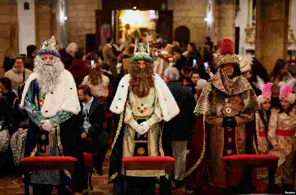Juan Miguel Aguilar, Diego Sanchez and Angel Ballesteros dressed up as Melchior, Gaspar and Balthazar, the Three Wise Men, worship a statue of Christ inside a church, as they tour the city center visiting churches, ahead of the Epiphany parade, in Ronda, Spain, Jan. 4, 2025. 