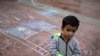 A child stands on a pavement adorned with chalk drawings at the El Chaparral U.S.-Mexico border crossing, in Tijuana, Mexico, May 2, 2018.
