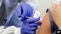 Neal Browning receives a shot in the first-stage safety study clinical trial of a potential vaccine for COVID-19, the disease caused by the new coronavirus, Monday, March 16, 2020, at the Kaiser Permanente Washington Health Research Institute in Seattle. 