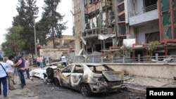 Wartawan dan penduduk sipil berdiri dekat rumah bersalin al-Dabit yang rusak terkena roket. Aleppo, Suriah. (Foto: SANA)