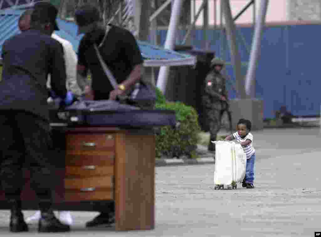 A child pushes a suitcase towards Rwanda security officials checking people crossing from Congo in Gisenyi, Rwanda, following M23 rebels' advances into eastern Congo's capital Goma.
