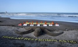 Para aktivis greenpeace berpose di sebelah penyu dari pasir dalam demo menuntut perusahaan besar di seluruh dunia untuk setop menggunakan wadah plastik, di Boca del Rio, Veracruz, Meksiko, 15 April 2018. (Foto: AFP)