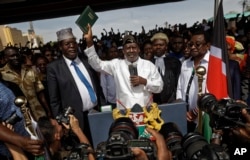 FILE - Opposition leader Raila Odinga (C) accompanied by lawyers Miguna Miguna (C-L), Tom "T.J." Kajwang, (C-R) and politician James Orengo (R) holds a bible aloft after swearing an oath during a mock "swearing-in" ceremony at Uhuru Park in downtown Nairobi, Kenya, Jan. 30, 2018.