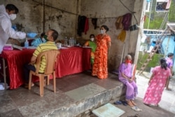 Seorang petugas kesehatan (kiri) mengenakan Alat Pelindung Diri (APD), melakukan tes swab untuk Covid-19 di Mumbai, 19 Agustus 2020. (Foto: INDRANIL MUKHERJEE / AFP)