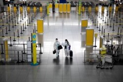 Passengers wearing hazmat suits for protection against COVID-19 walk through the Ninoy Aquino International Airport in Paranaque, Metro Manila, Philippines.