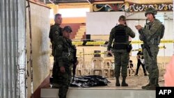 FILE - Personel militer berjaga di pintu masuk gimnasium sementara penyelidik polisi (latar belakang) mencari bukti setelah serangan bom di Universitas Negeri Mindanao di Marawi, provinsi Lanao del sur, 3 Desember 2023. (MERLYN MANOS / AFP)
