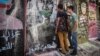 Young Lebanese peer through a gap in the wall, which was erected Monday in Beirut in the wake of clashes with protesters over the weekend. (Credit: John Owens/VOA)