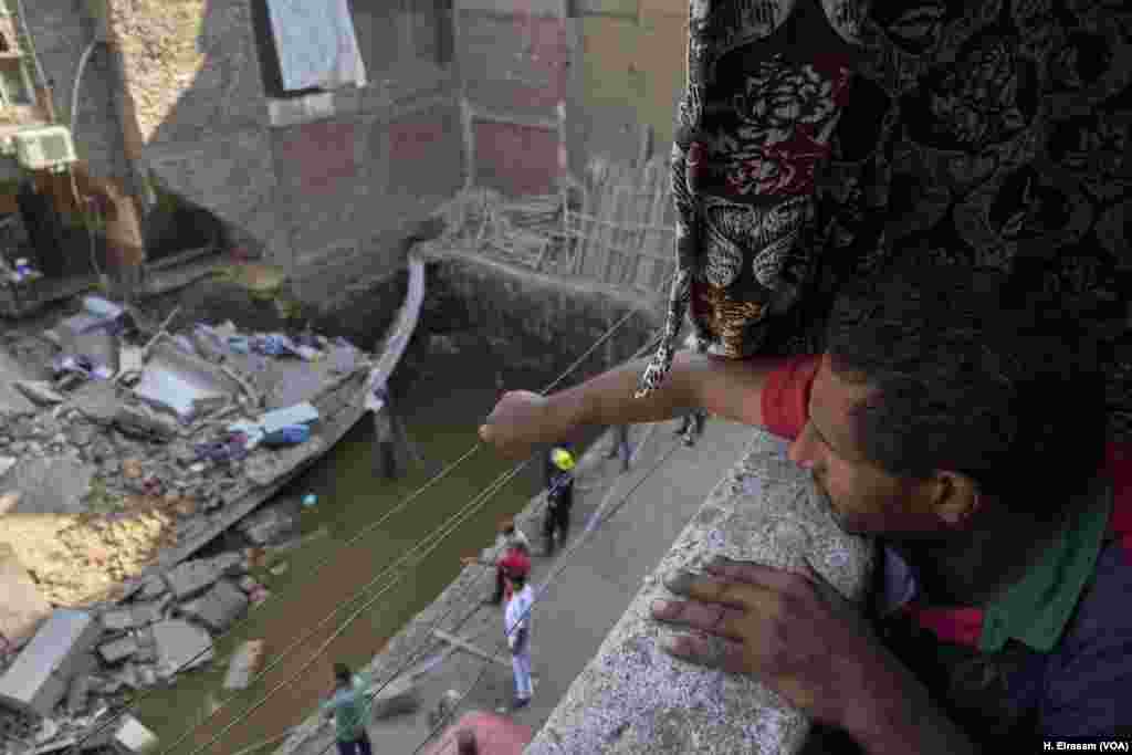 Ramy, a resident of Shobra, an informal neighborhood in northern Cairo, watches as survivors are sought in a collapsed building. Many buildings have gone up without permits, soil surveys or inspections. Ramy worries the collapse may not stop there and his home could be next. “Buildings are like dominos here.”