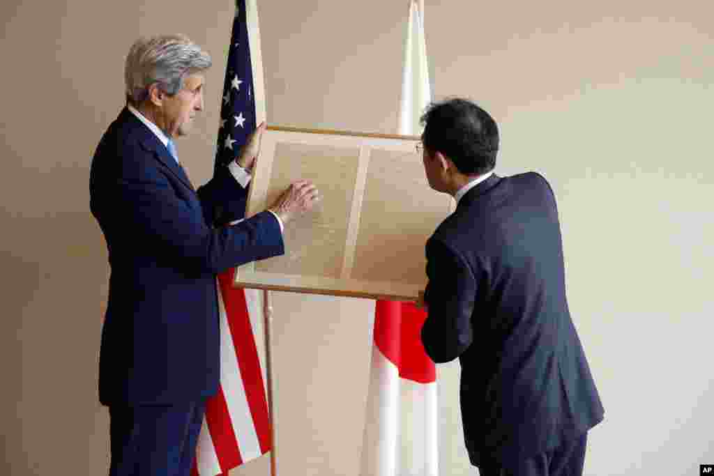 U.S. Secretary of State John Kerry, left, points out to Japan's Foreign Minister Fumio Kishida a passage about friendship in a replica of a letter on a small diplomatic matter from former U.S. President Abraham Lincoln to the Tycoon of Japan in 1861, before their bilateral meeting in Hiroshima, Japan, April 11, 2016.
