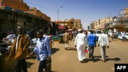 People walk in front of shops at a market in the Sudanese capital, Khartoum, Feb. 21, 2021. Sudan has ratified U.N. conventions against torture and enforced disappearances, after months of delay. 