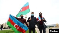 People pose with national flags as they celebrate the entry of the Azerbaijan army units in the Aghdam region of Nagorno-Karabakh, in Baku, Azerbaijan Nov. 20, 2020. 