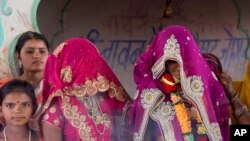 An underaged bride, right, stands with family members during her marriage at a Hindu temple near Rajgarh, Madhya Pradesh state, India, April 17, 2017.