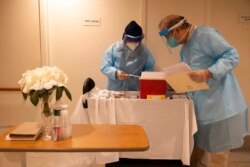 CVS pharmacists prepare the COVID-19 vaccine for the nursing home residents at Harlem Center for Nursing and Rehabilitation, Jan. 15, 2021, in the Harlem neighborhood of New York.