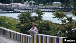 FILE - A man sits on a boundary wall near the Indus river in Gilgit.