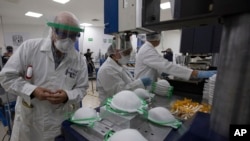 Seorang petugas memeriksa masker yang baru diproduksi di sebuah pabrik di Mexico City, 21 Mei 2020. 