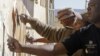 Members from the South African correctional service repair a wall at a school where former South African President Nelson Mandela went as a child as they celebrate his birthday in Qunu, South Africa, Wednesday, July 18, 2012.
