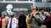 Para pengunjung berkumpul di depan foto Kobe Bryant yang dipasang di layar lebar di luar Staples Center setelah mantan pebasket klub Los Angeles Lakers tewas dalam kecelakaan helikopter, di Los Angeles, California, 26 Januari 2020. 