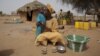 FILE - Maryam Sy comforts her 2-year-old son Aliou Seyni Diallo, the youngest of nine, after a neighbor gave him dry couscous to stop him from crying with hunger, May 1, 2012. 