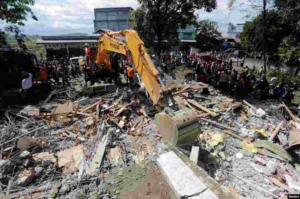 Para petugas penyelamat menggunakan peralatan berat untuk mencari para korban di bawah bangunan yang ambruk akibat gempa bumi di Lueng Putu, Pidie Jaya, Aceh (7/12). (Reuters/Antara/Irwansyah Putra)