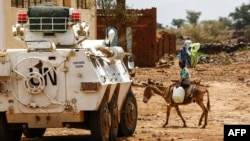 Seorang anak laki-laki Sudan mengendarai keledai melewati kendaraan lapis baja PBB-Uni Afrika di Darfur (UNAMID) di kota Golo yang dilanda perang, di daerah pegunungan berhutan lebat Jebel Marra, Darfur tengah, 19 Juni 2017. (Foto: dok).